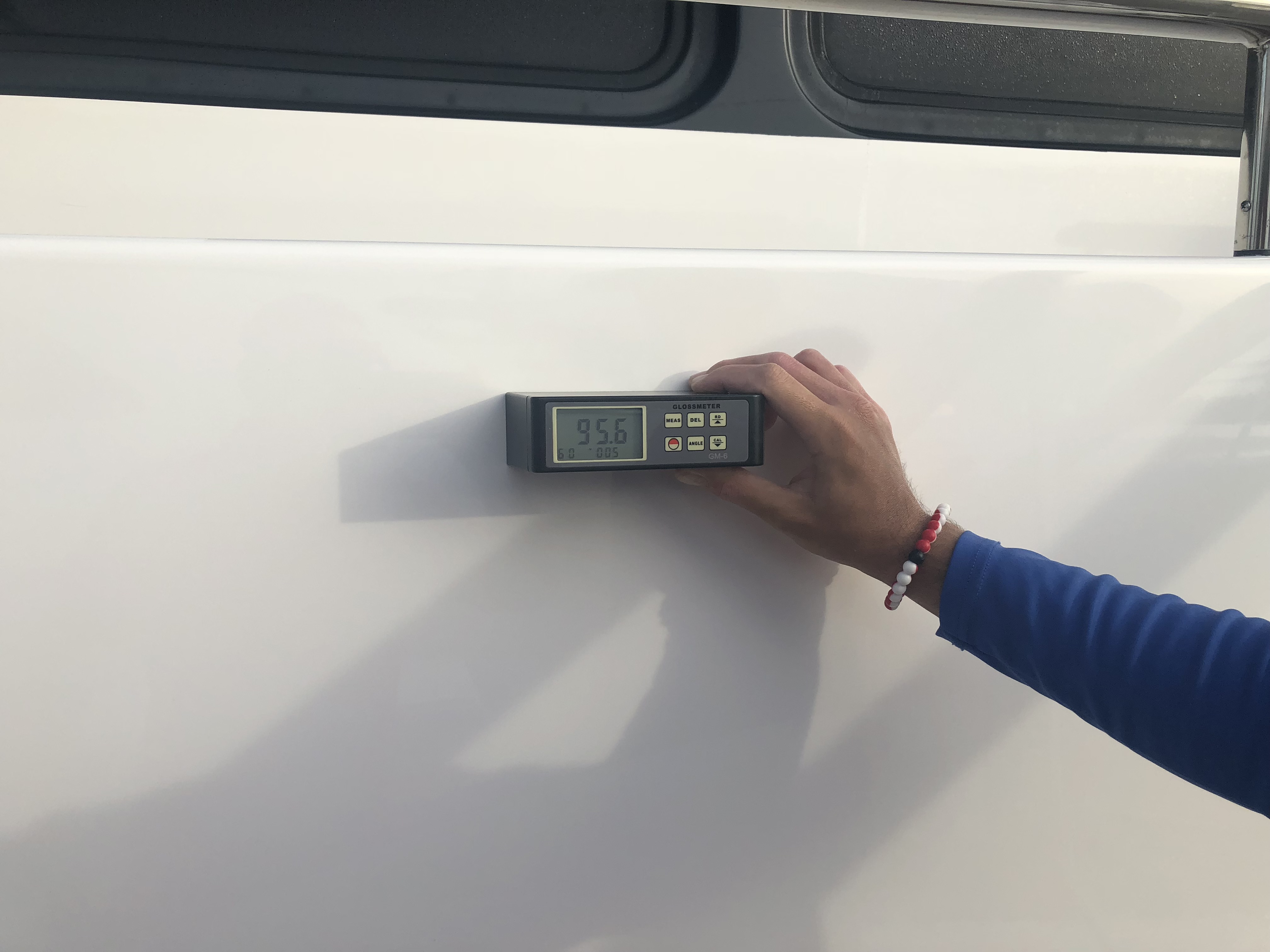 Man holding the gloss meter with 95.6 reading on the 95' Heisley after Glidecoat ceramic coating application