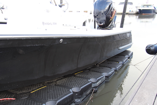 Faded and oxidized hull of a Blackjack 224 sitting on a floating dock