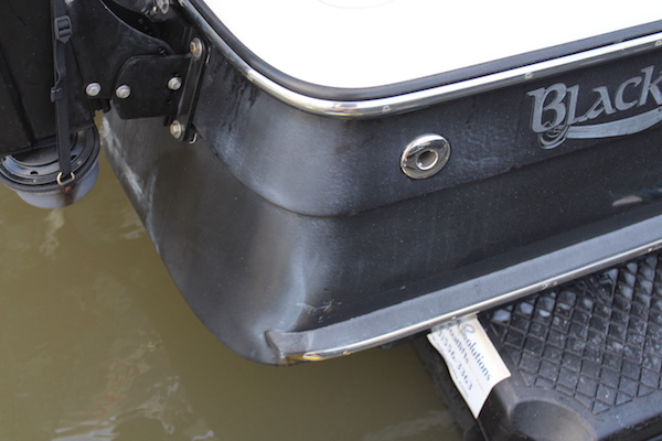 Faded and oxidized transom of a Blackjack 224 sitting on a floating dock